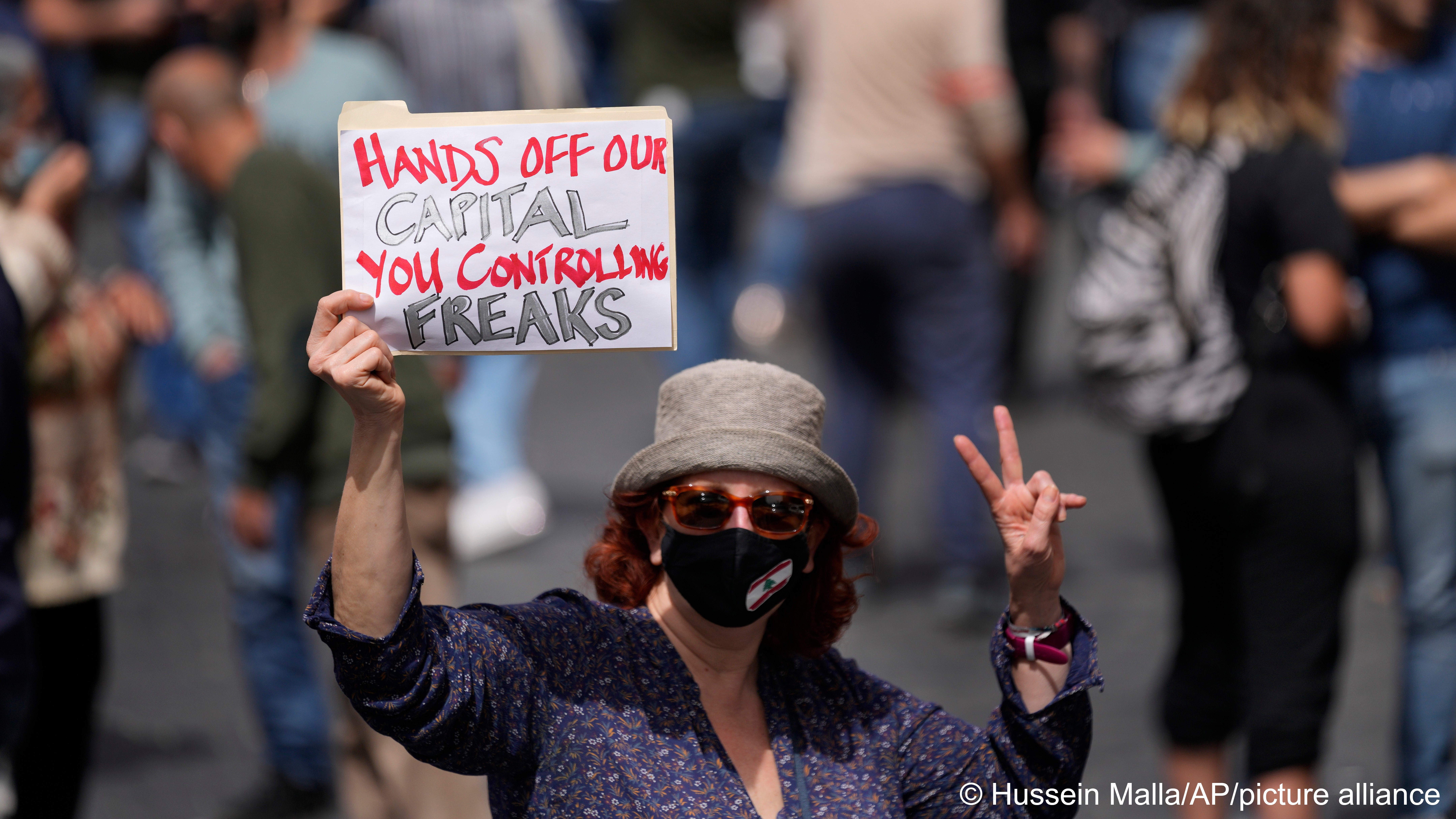 A demonstrator holds a placard during a protest against a new draft law on capital controls on savings withdrawals outside the parliament building, in downtown Beirut, Lebanon, Tuesday, April 26, 2022 (photo: AP Photo/Hussein Malla)