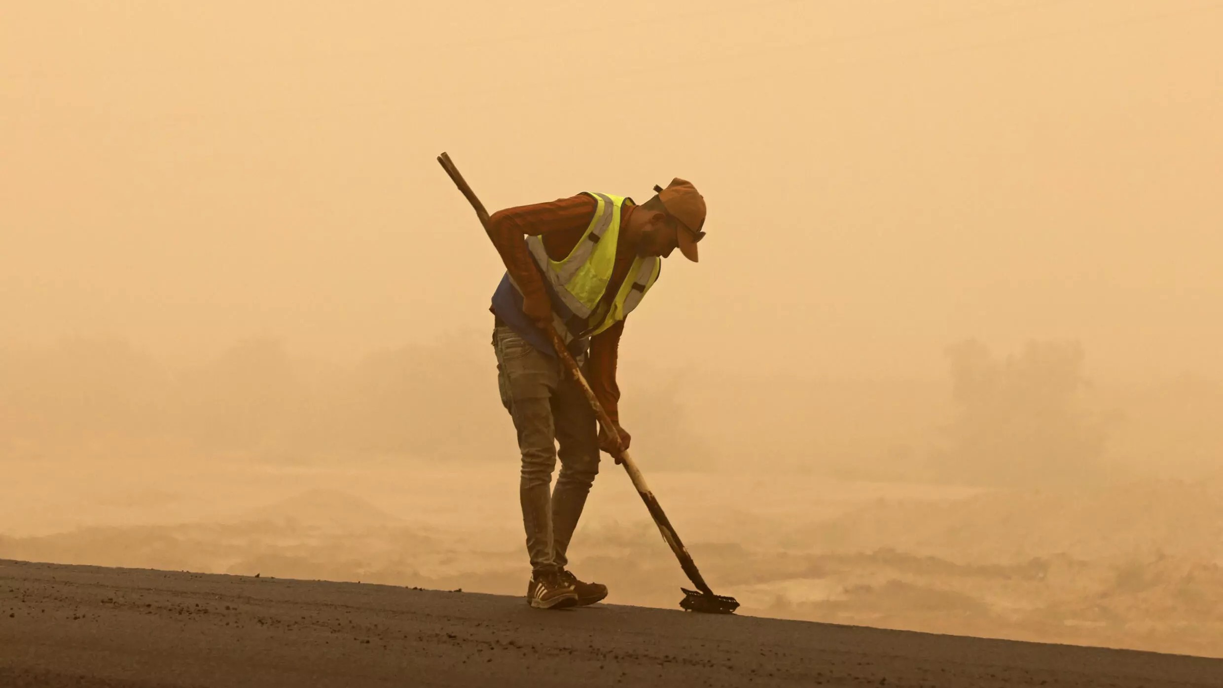 A worker sweeps a road during a sandstorm in Iraq's Diyala province, on July 3: oil-rich Iraq is ranked one of the five countries most vulnerable to the impacts of climate change and desertification (photo: AHMAD AL-RUBAYE/AFP) 
