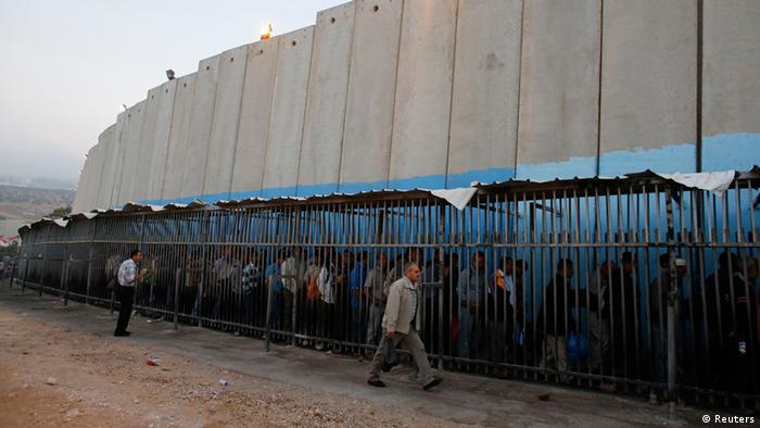 فحوصات أمنية عند الجدار الخرساني الذي يفصل إسرائيل عن الأراضي الفلسطينية المحتلة. Palestinians from the Occupied Territories wait at the border wall to cross into Israel to work (photo: Reuters)