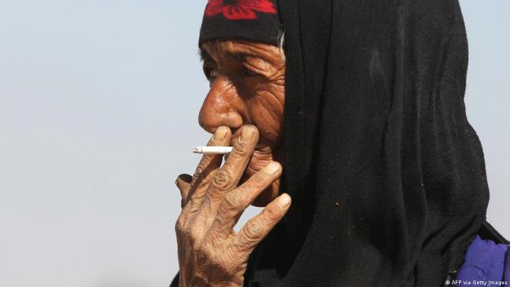 A elderly Iraqi woman smoking a cigarette (photo: AFP via Getty Images)