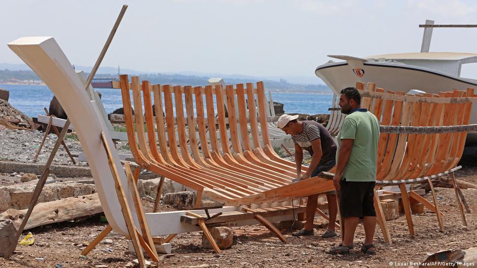 Syrian craftsman Khaled Bahlawan (r) builds a wooden boat at his boatyard in Syria's Mediterranean Island of Arwad on 24 July 2022 (photo: LOUAI BESHARA/AFP/Getty Images)