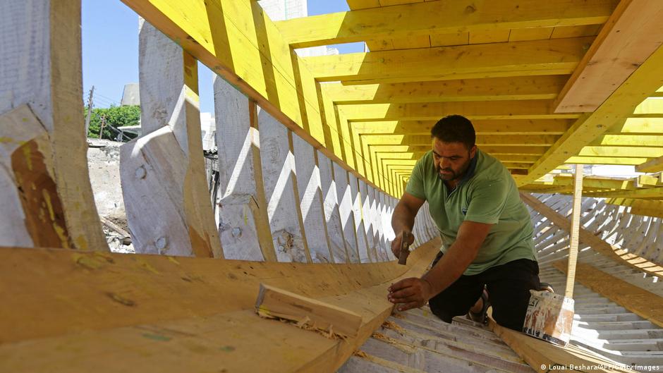 Syrian craftsman Khaled Bahlawan hammers nails in a wooden boat at his boatyard in Syria's Mediterranean Island of Arwad on 24 July 2022 (photo: LOUAI BESHARA/AFP/Getty Images)