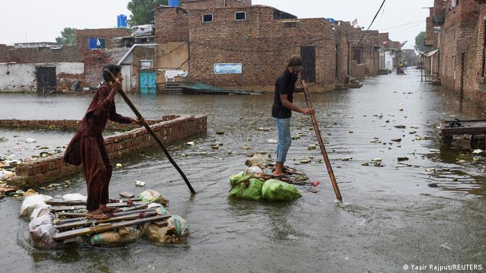Two young men paddle through the streets of Hyderabad on homemade rafts