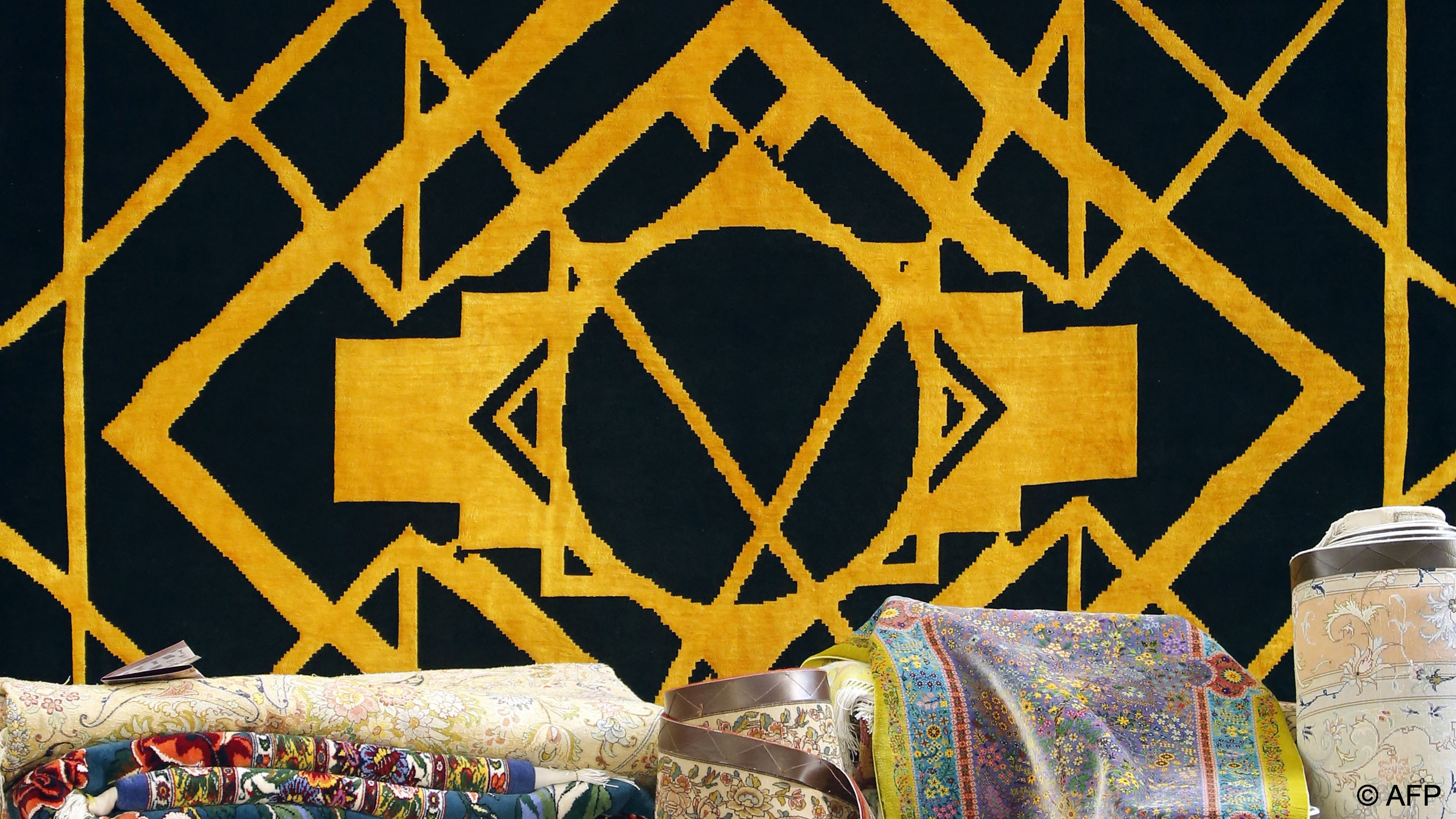 Rug depicting diamond and other geometric patterns in gold silk on a black background (photo: AFP)