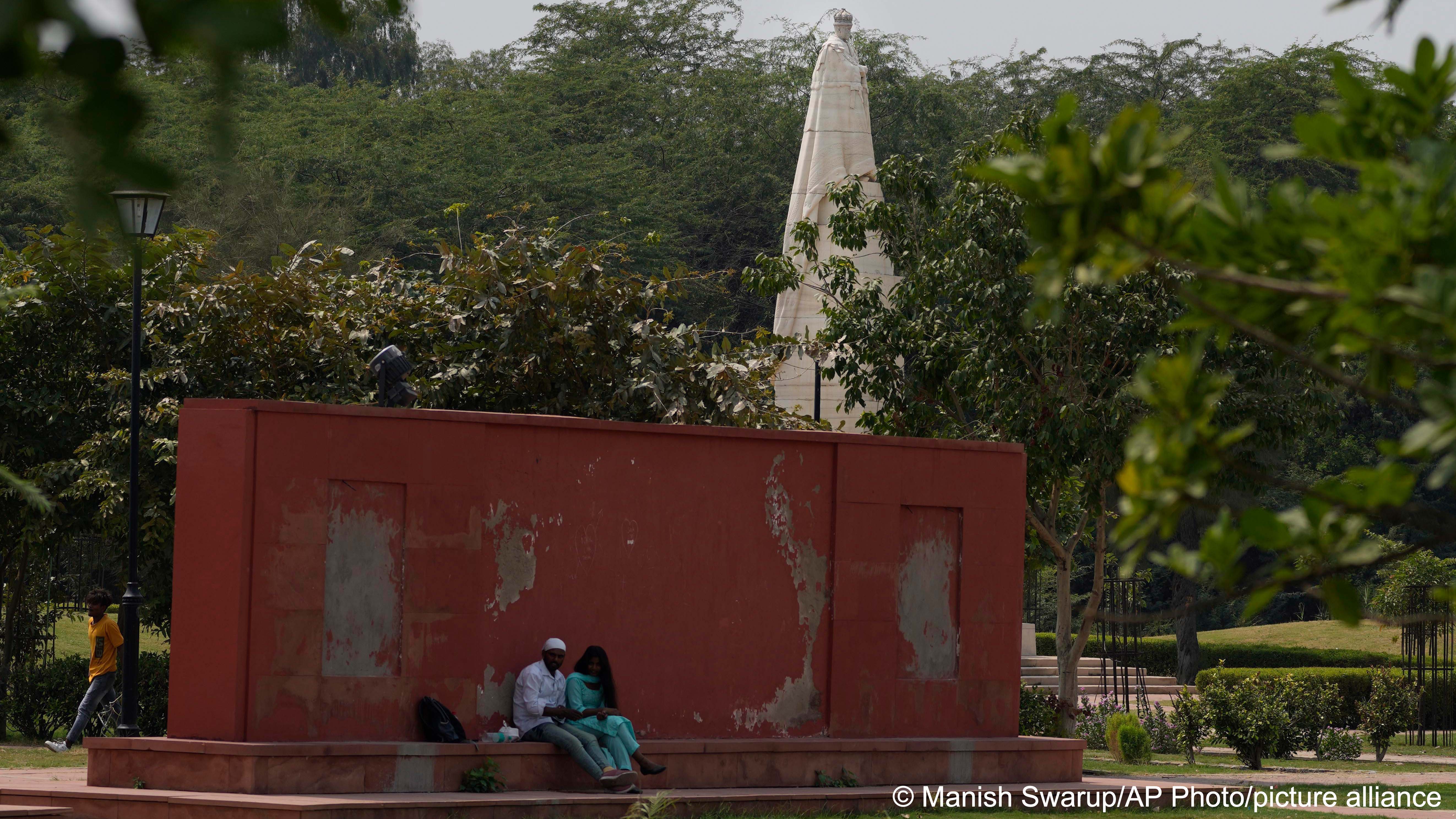 A couple sits near a statue of King George V in coronation park, which houses statues of old British Kings and rulers in New Delhi, 11 September 2022 (photo: AP Photo/Manish Swarup)