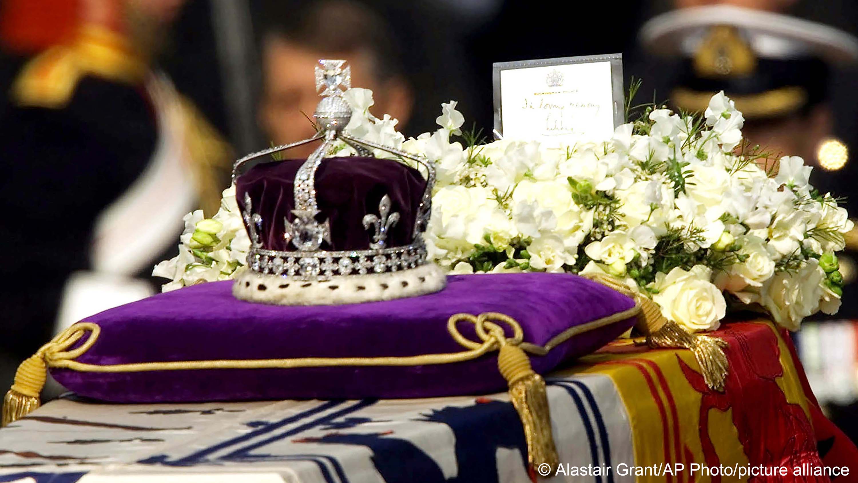 The Koh-i-noor, or "mountain of light", diamond, set in the Maltese Cross at the front of the crown made for Britain's late Queen Mother Elizabeth, is seen on her coffin, along with her personal standard, a wreath and a note from her daughter, Queen Elizabeth II, as it is drawn to London's Westminster Hall, 5 April 2002 (photo: AP Photo/Alastair Grant, File)