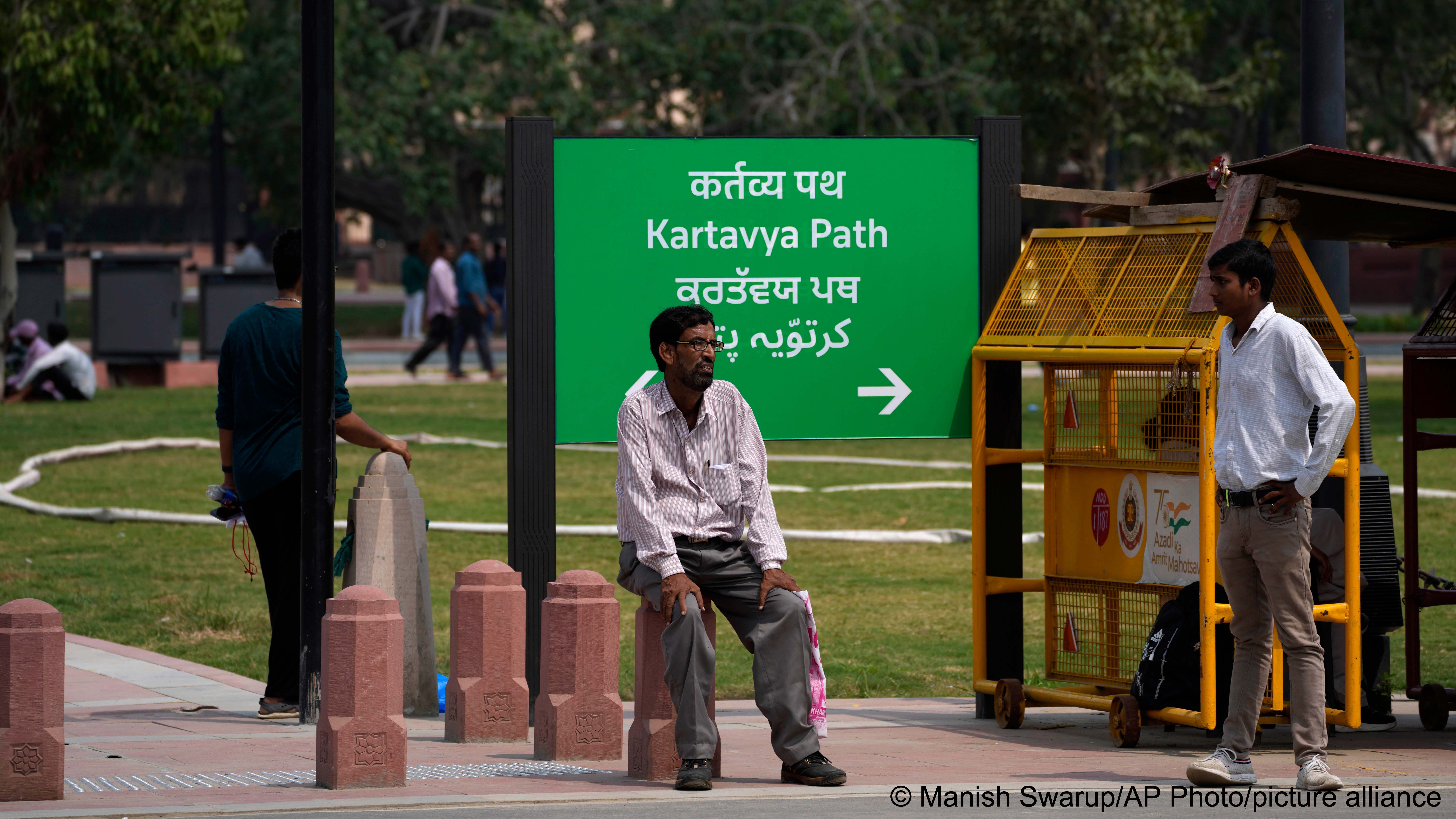 A man rests on a newly constructed pillar in front of a road signage which is changed from Rajpath to Kartavya Path, in New Delhi, 11 September 2022 (photo: AP Photo/Manish Swarup)