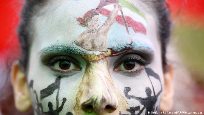 Painted face of a woman, showing the Iranian flag and protesters