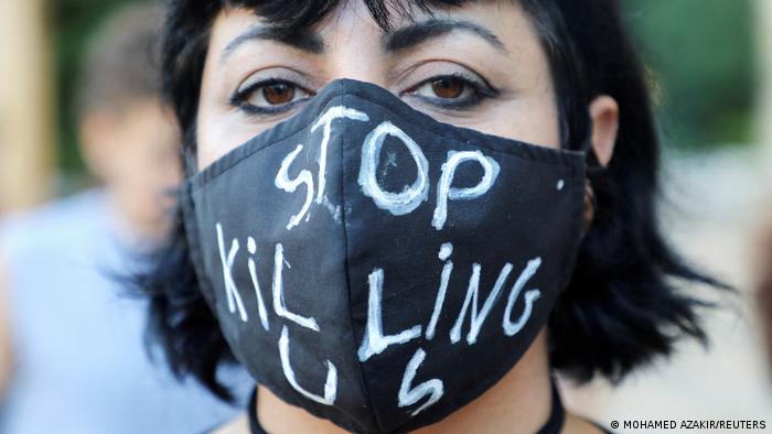 Woman wears a black face mask that reads "Stop killing us"
