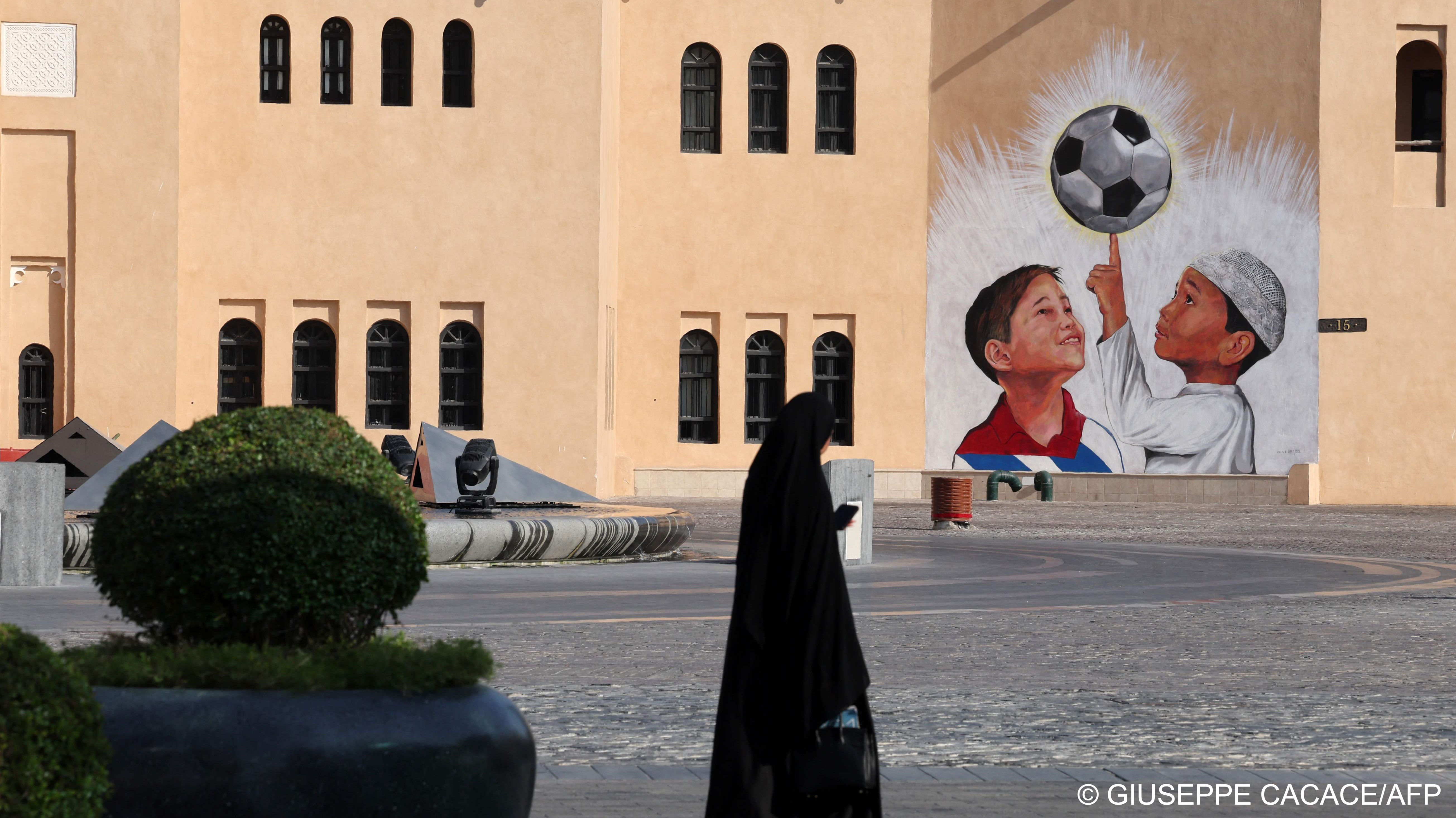 A woman walks past a mural in the Katara Cultural Village, in Qatar's capital Doha, on October 11, 2022 ahead of the FIFA 2022 football World Cup (photo: Giuseppe CACACE/AFP) 