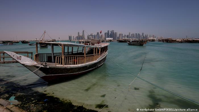 A wooden boat with the skyline of Doha in the background
