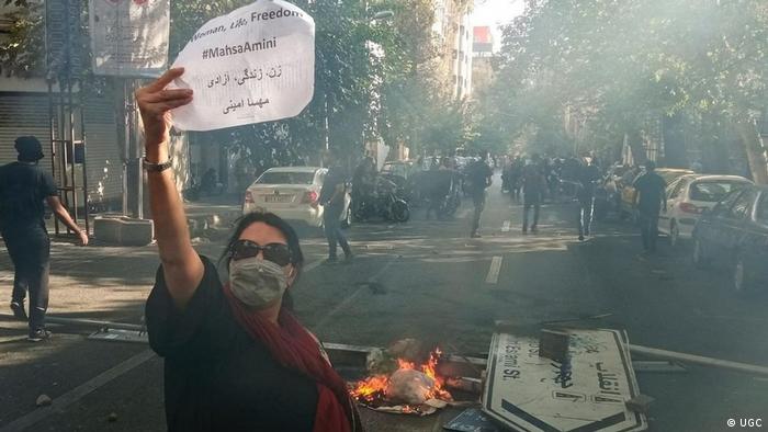 Femal protester in Iran holds up a sheet of paper bearing the words "Woman, Life, Freedom" in English and Farsi (photo: UGC)