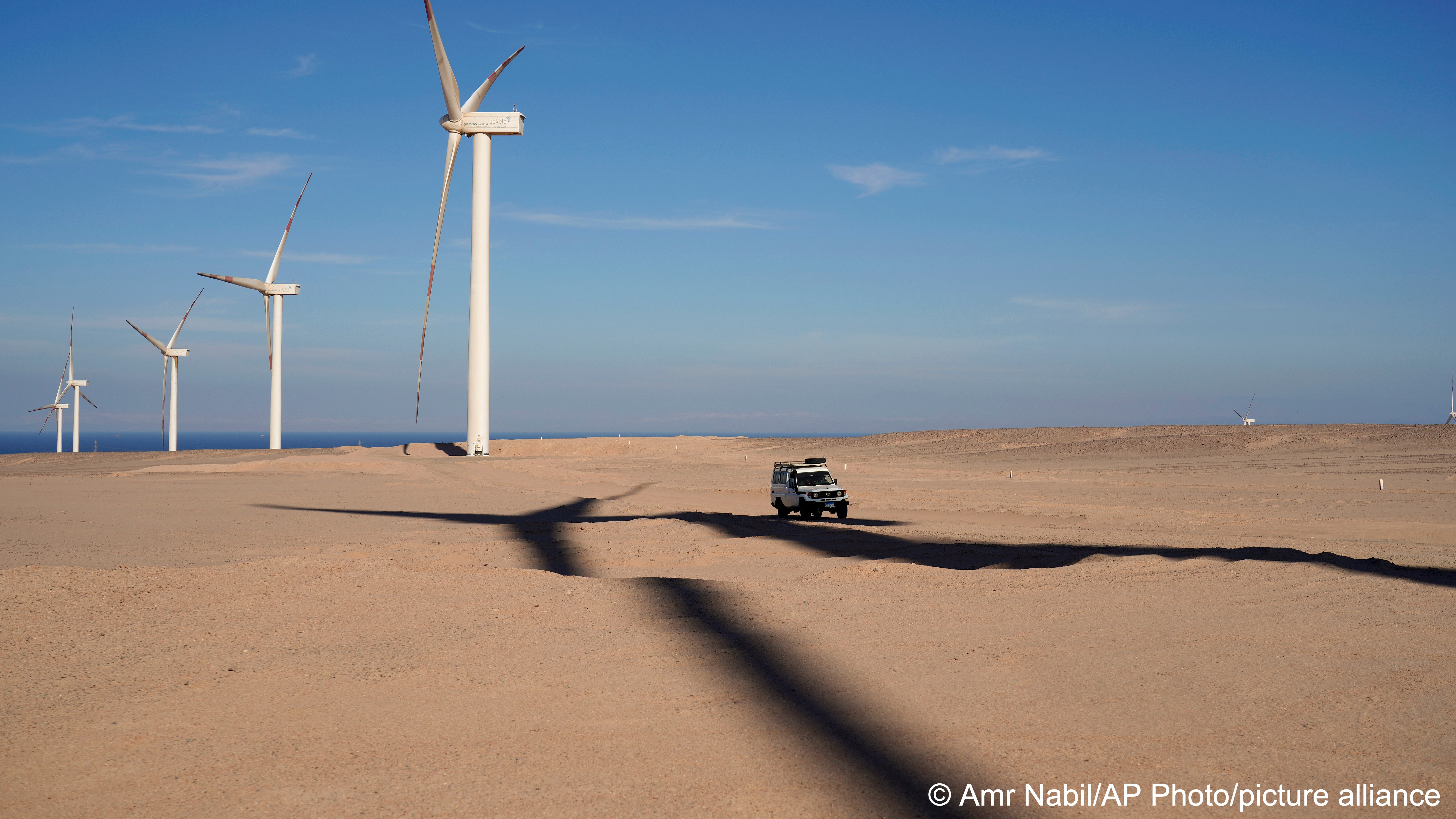 A vehicle drives near wind turbines at Lekela wind power station, near the Red Sea city of Ras Ghareb, some 300 km from Cairo, Egypt, 12 October 2022 (photo: AP Photo/Amr Nabil)