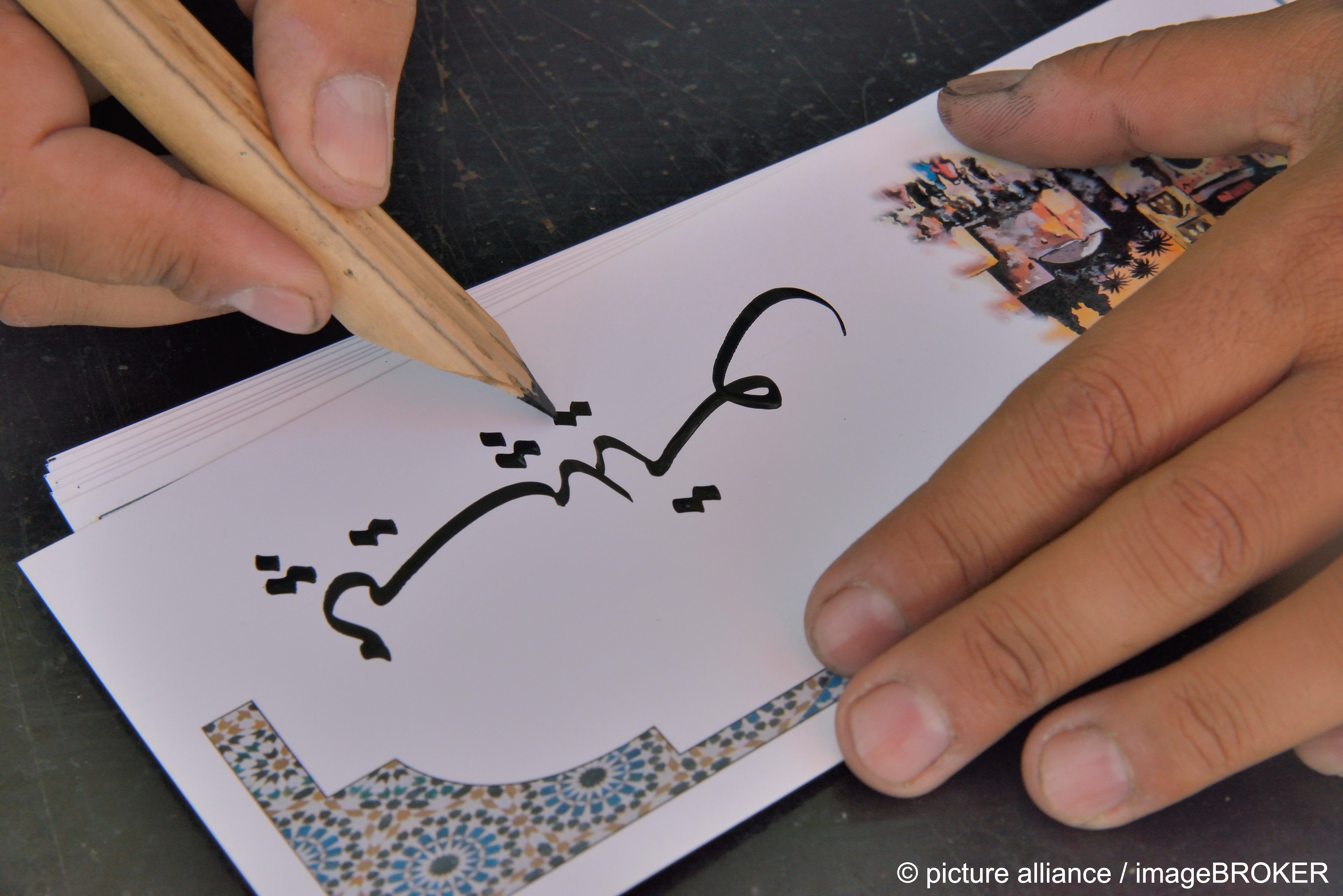 شخص يكتب على ورقة بيضاء وحِبر أسْوَد بالخط العربي. Arabic script Photo Picture Alliance