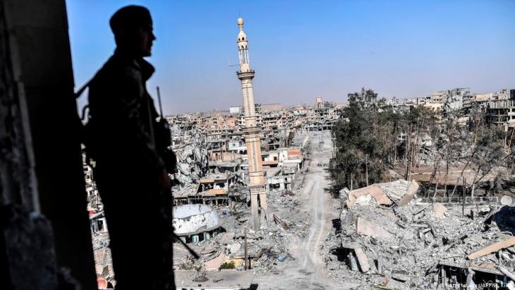 A fighter looks out over the devastated city of Raqqa in Syria after it was re-taken from IS by Kurdish militias (photo: Getty Images/AFP/B. Kilic)