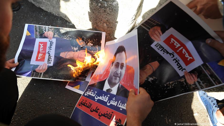A poster with a picture of Judge Tarek Bitar who is investigating the deadly seaport blast in Beirut August 2020, is set on fire by supporters of the Shia Hezbollah and Amal groups, during a protest in front of the Justice Palace, in Beirut, Lebanon, on 14 October 2021 (image: Jamal Eddine/newscom/picture-alliance)