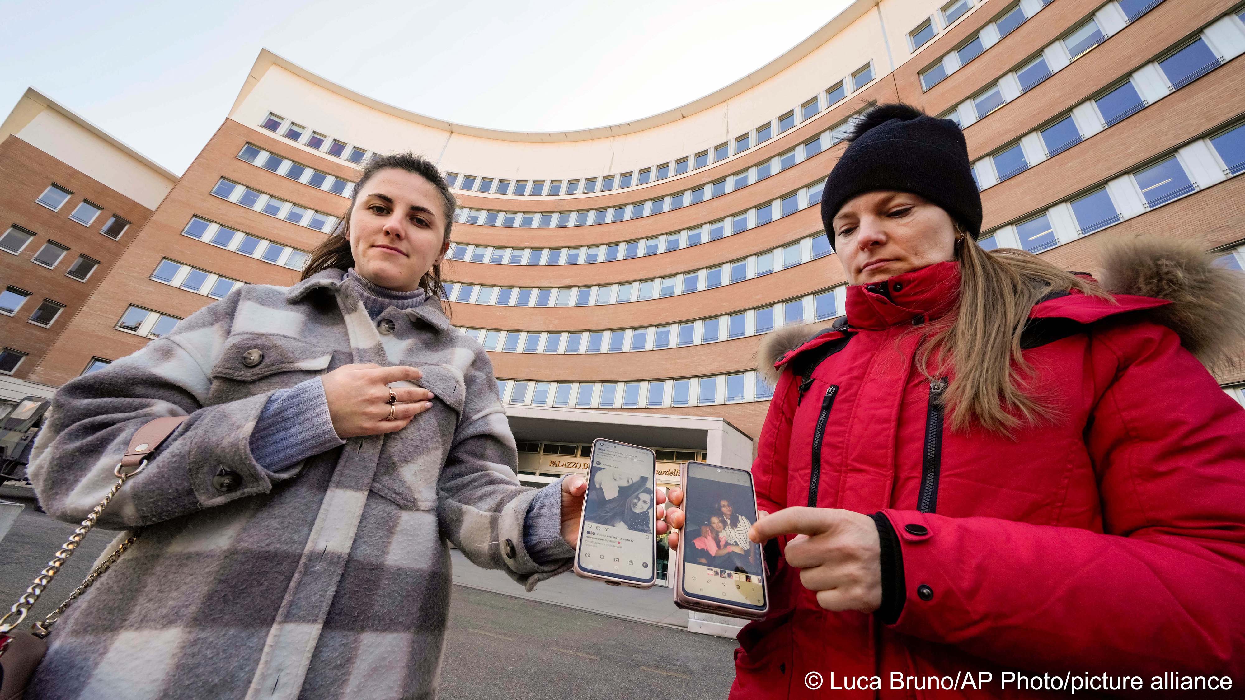 erkalets Olha from Ukraine, right, and Veronica Catana of Moldova, show their smartphones with pictures of their Pakistani-born friend Sana Cheema before testifying in a trial about her alleged murder outside the courthouse in Brescia, northern Italy, 9 February 2023 (image: Luca Bruno/AP Photo/picture alliance) 