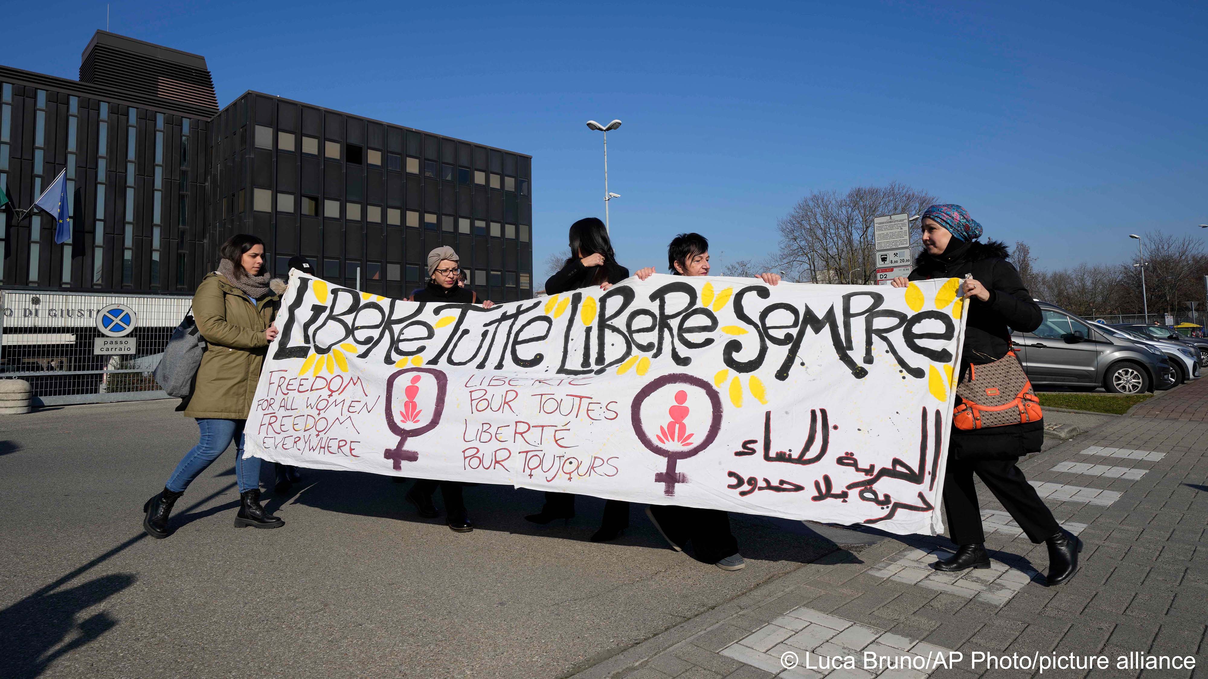 Activists of the ‘Trama di Terre’ (Weaving of Native Lands) and other women’s advocacy groups display a banner in Italian reading ‘Freedom for all women, forever free’, outside the Reggio Emilia courthouse in northern Italy, during the opening session of trial for the alleged murder of Pakistani-born Saman Abbas on 10 February 2023 (image: Luca Bruno/AP Photo/picture alliance) 