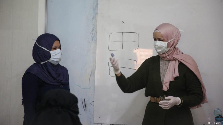 هدى خياطي (يمين) تقف أمام لوح أبيض مع امرأة أخرى في مركز نسائي في إدلب - سوريا. Huda Khayti (right) stands in front of a whiteboard with another woman in a women's centre in Idlib (image: Huda Khayti)