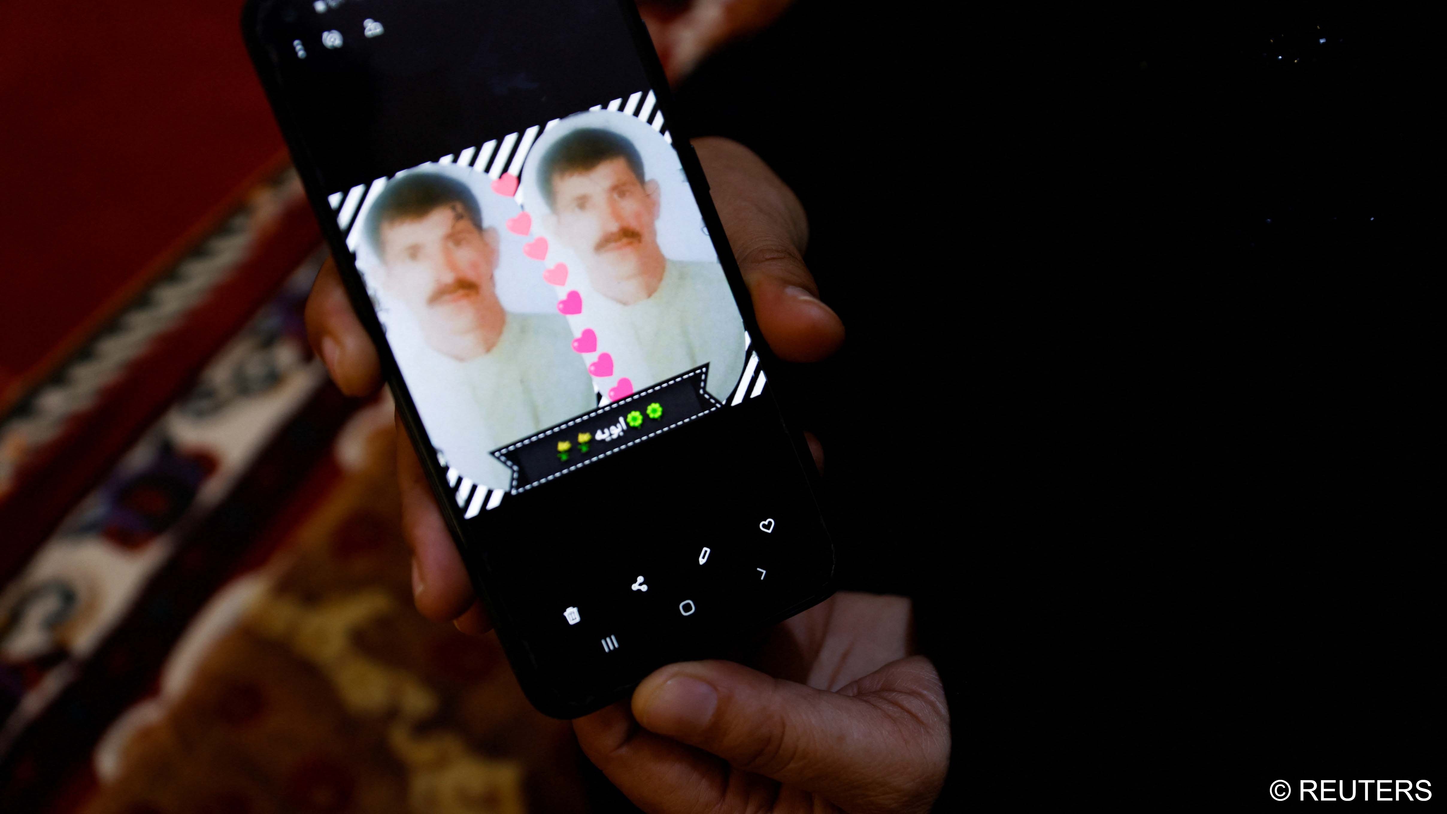 Ikhlas Talal, 43, shows a picture of her husband on the phone, who went missing as their area was liberated from Islamic State in 2016, in Saqlawiya, February 2023 (image: REUTERS/Saba Kareem)