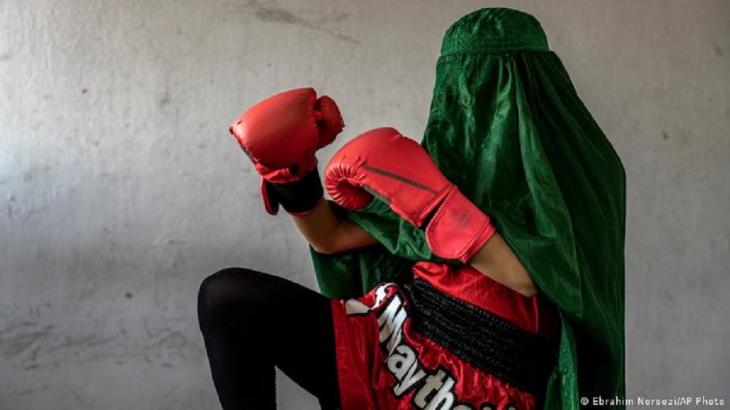 A young Thai boxer in Kabul wearing a burka and boxing gloves