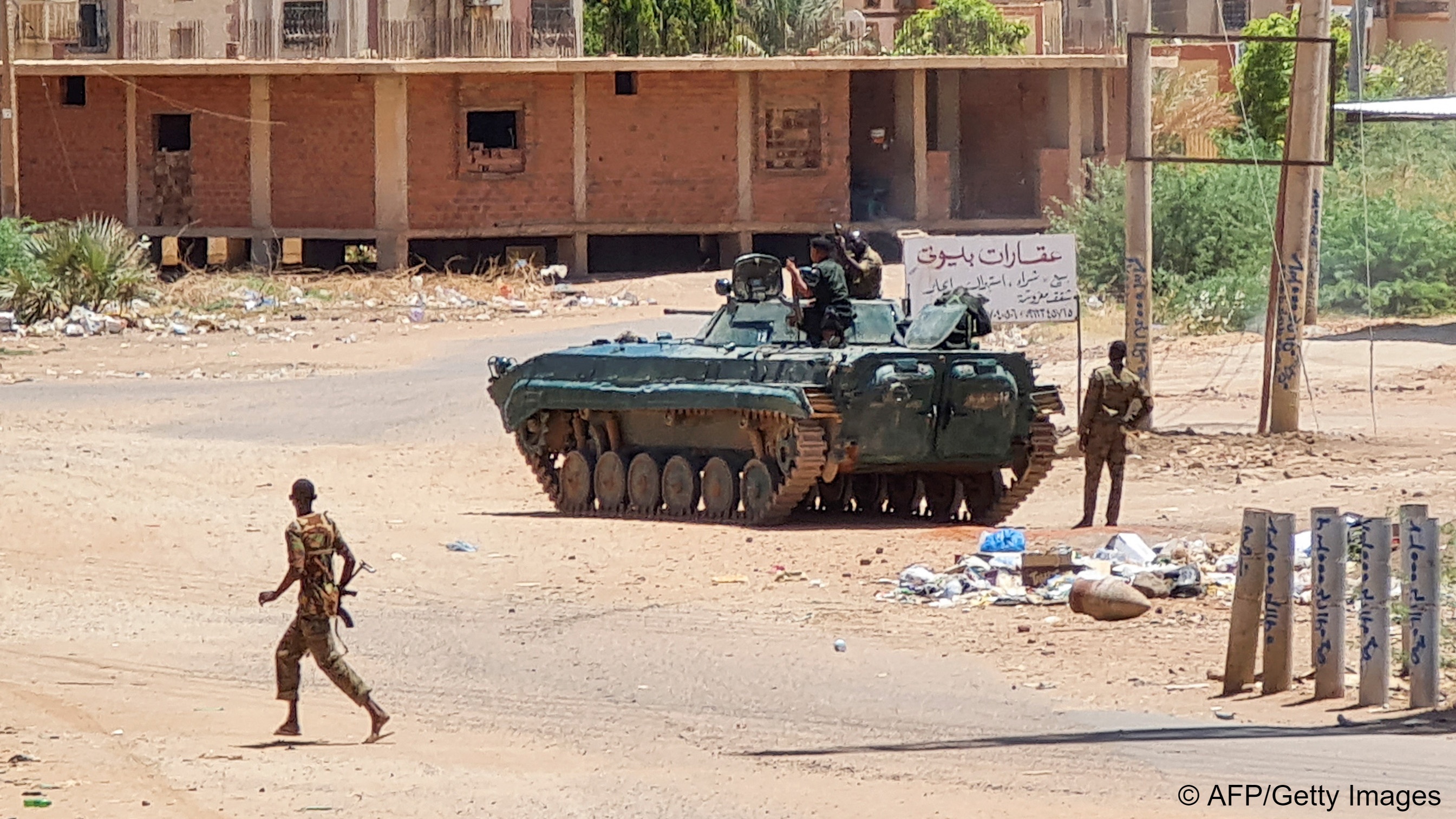 Sudanese Army soldiers walk near armoured vehicles stationed on a street in southern Khartoum, Sudan, 6 May  2023 (photo: AFP/Getty Images)