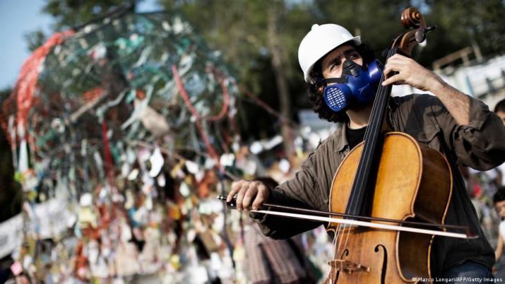 A cellist with a gas mask and a helmet plays the cello, Taksim Square, Istanbul, 15 June 2013 (photo: Marko Longari/AFP/Getty Images)