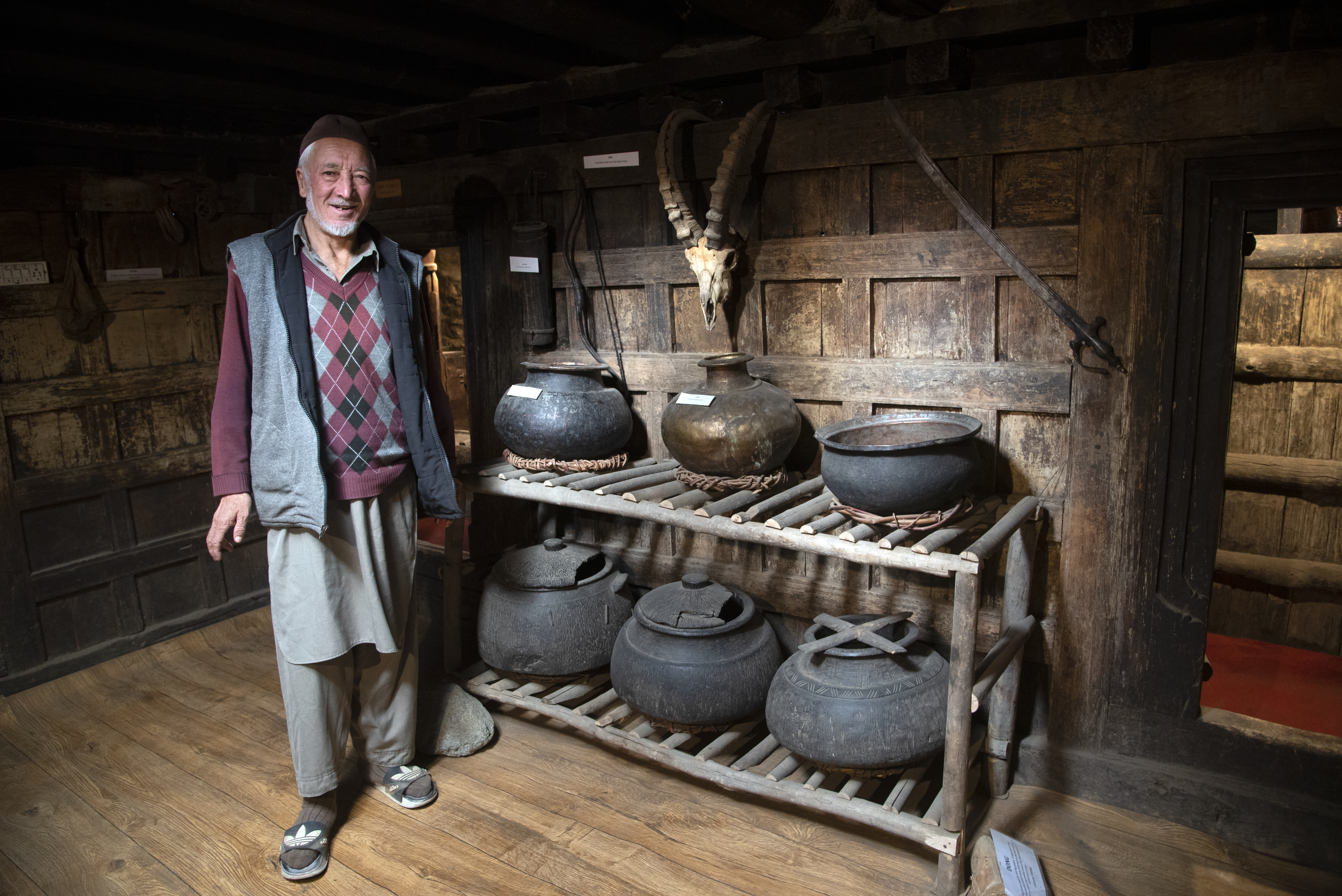 A man stands in front of a shelf holding cooking vessels (image: Sugato Mukherjee)