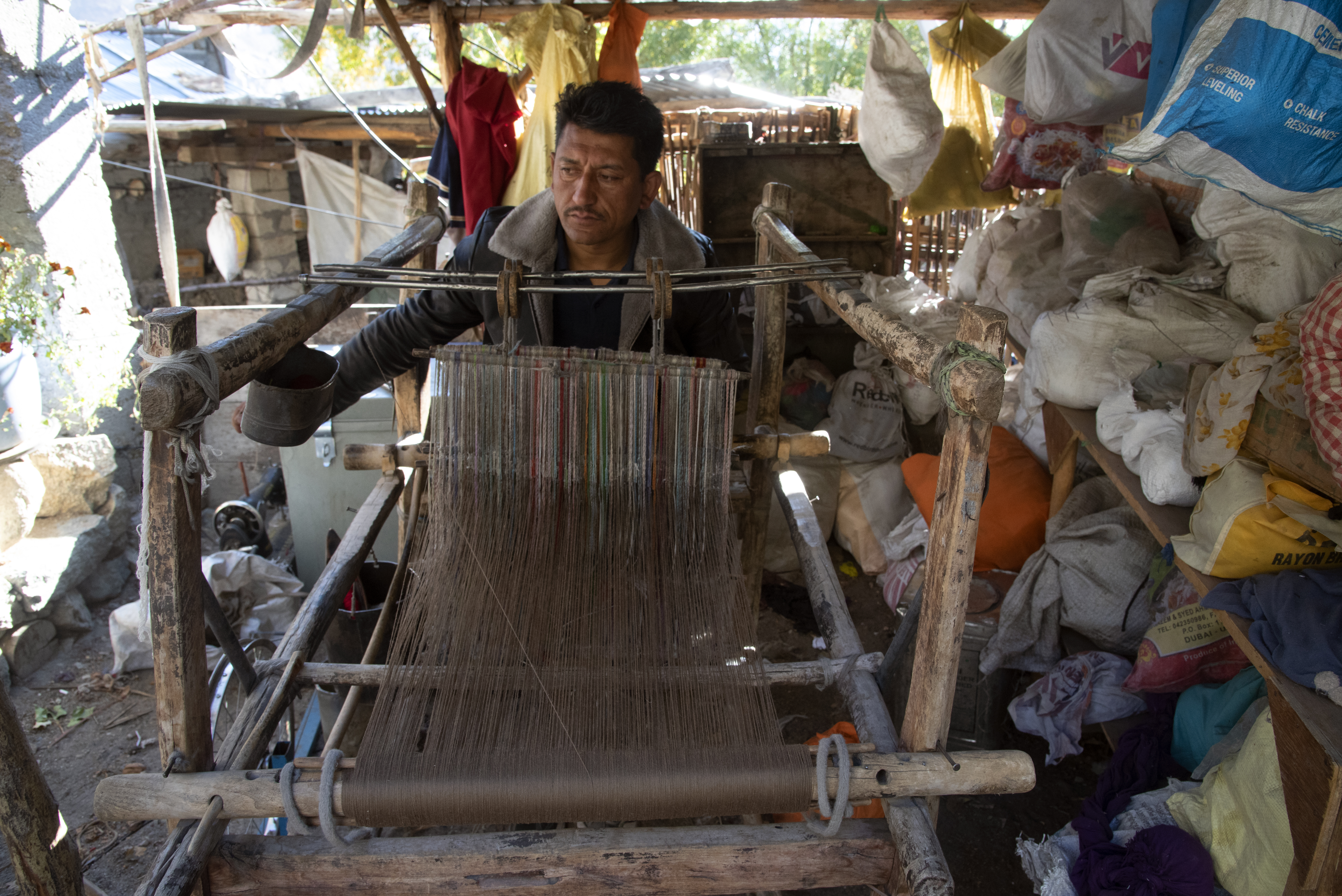 A man sits at a loom and weaves (image: Sugato Mukherjee)