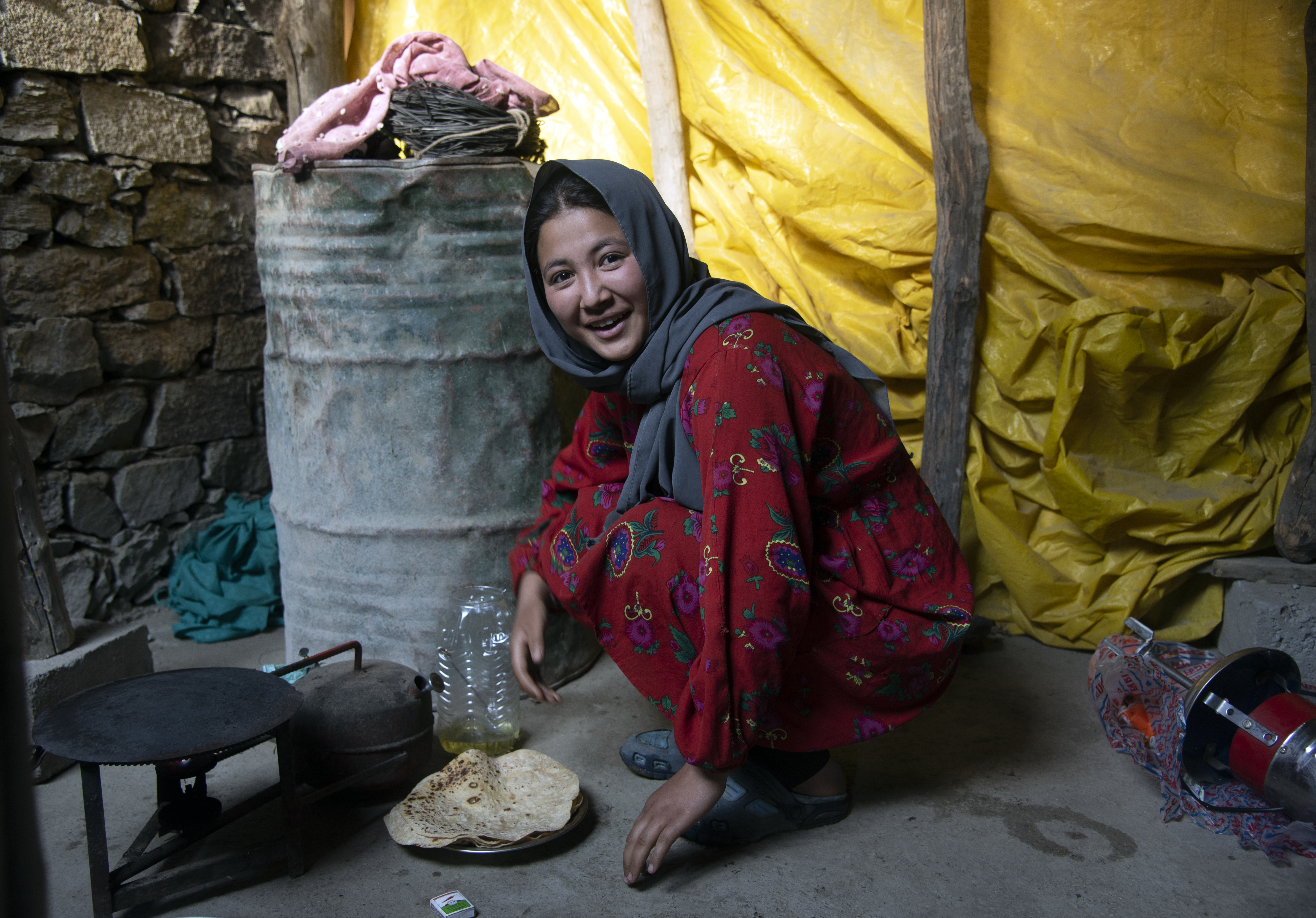 A woman squats, waiting for her water canister to fill at an outside tap (image: Sugato Mukherjee)