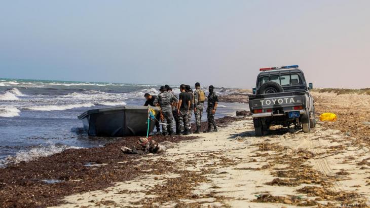 A group of armed men on an eastern Libyan beach inpsect a boat that was used to carry migrants (photo: Islam Altarash)