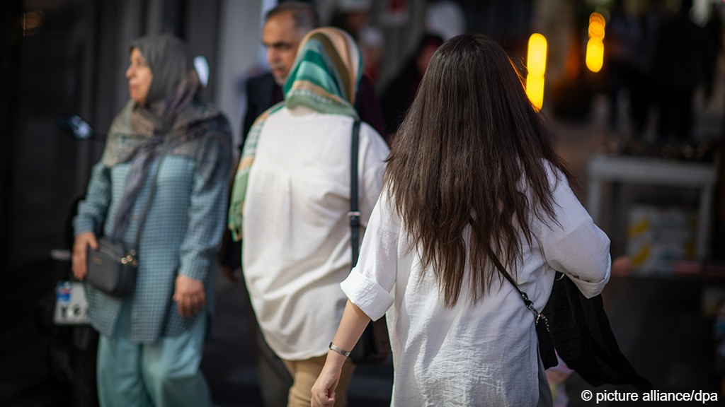 Women, one of whom does not have her hair covered, walk along a street in Tehran (photo: Arne Immanuel Bänsch/dpa/picture alliance)