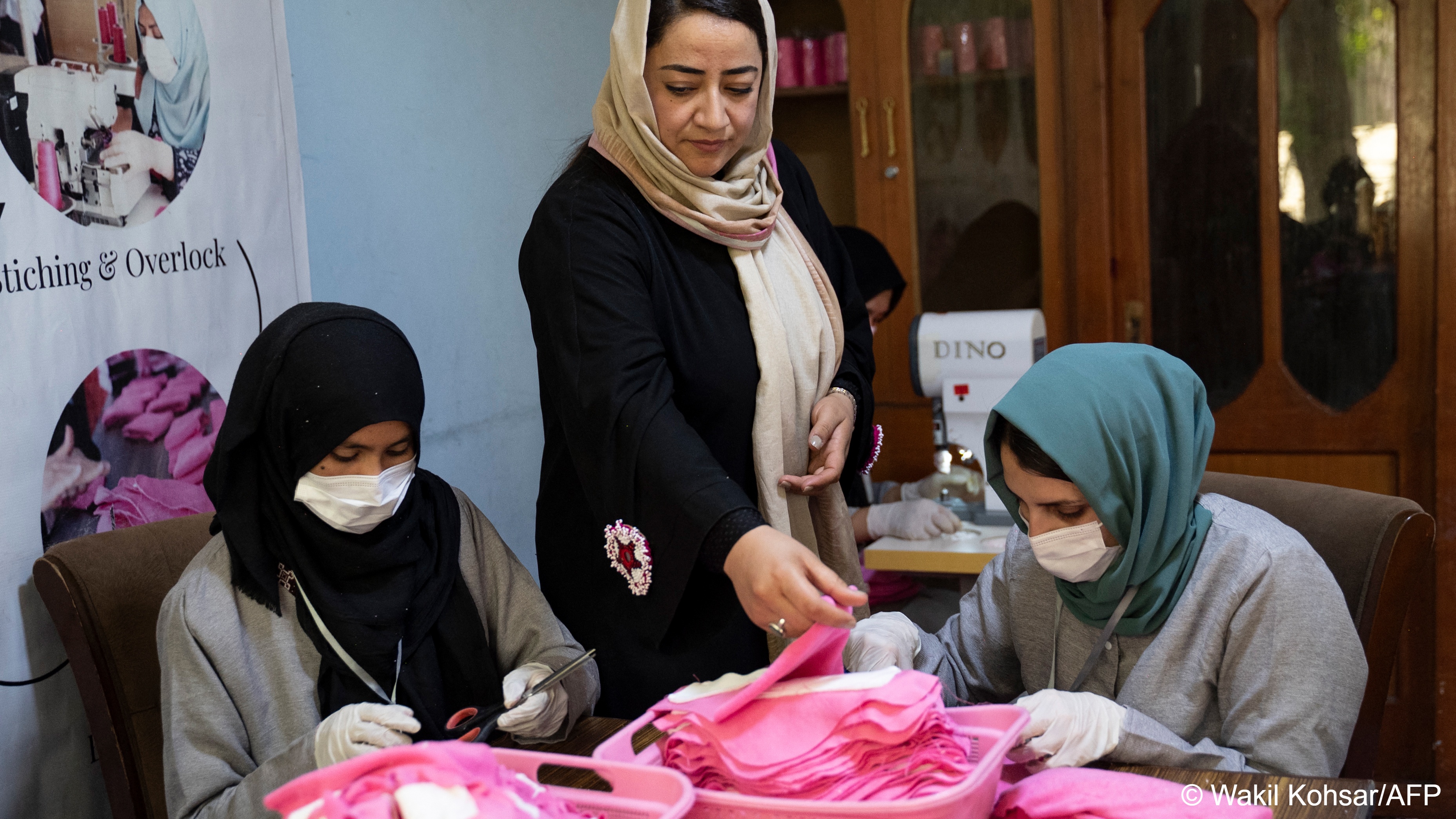 Afghan woman Arezo Osmani (centre), owner of Safe Path Prosperity Social Enterprise inspects a fabric sanitary pad in her tailor workshop in Kabul on 31 July 2023 (image: Wakil KOHSAR/AFP)