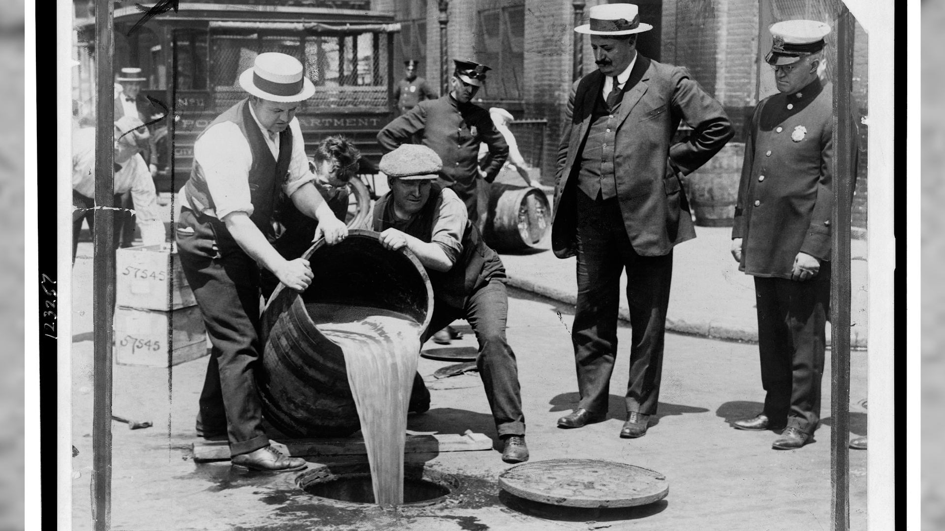 حظر الخمور في الولايات المتحدة الأمريكية. New York City Deputy Police Commissioner John Leach watching agents pour liquor into sewer following a raid during the height of prohibition 1920-1933 Photo Wikipedia.jpg
