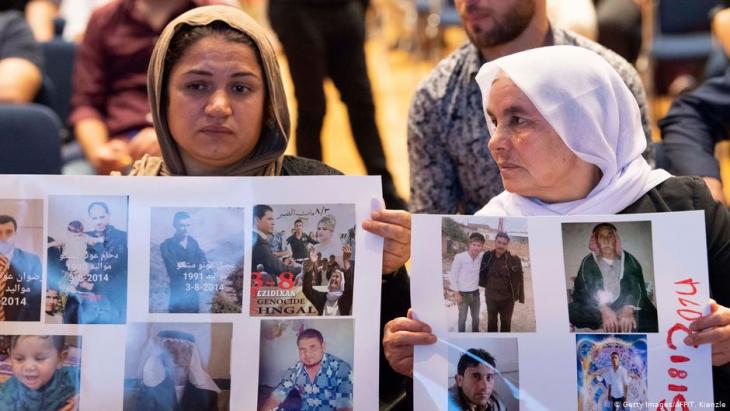 Yazidi women hold posters with photos of missing relatives at an event in Stuttgart, Germany, 2019 (image: Getty Images/AFP/R.Kienzle)