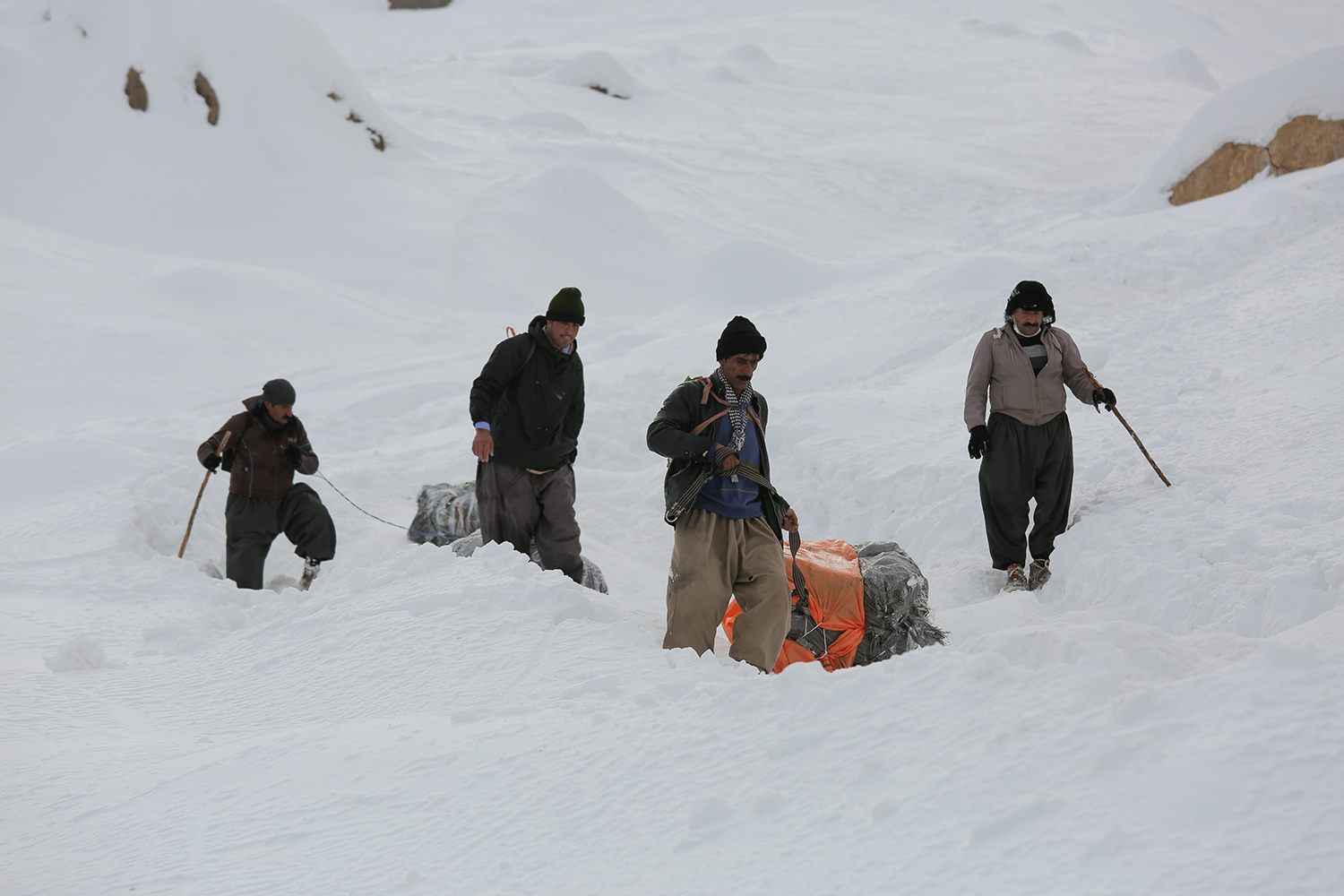 Vier Männer mit zwei Rucksäcken im Schnee; Foto: Konstantin Novakovic