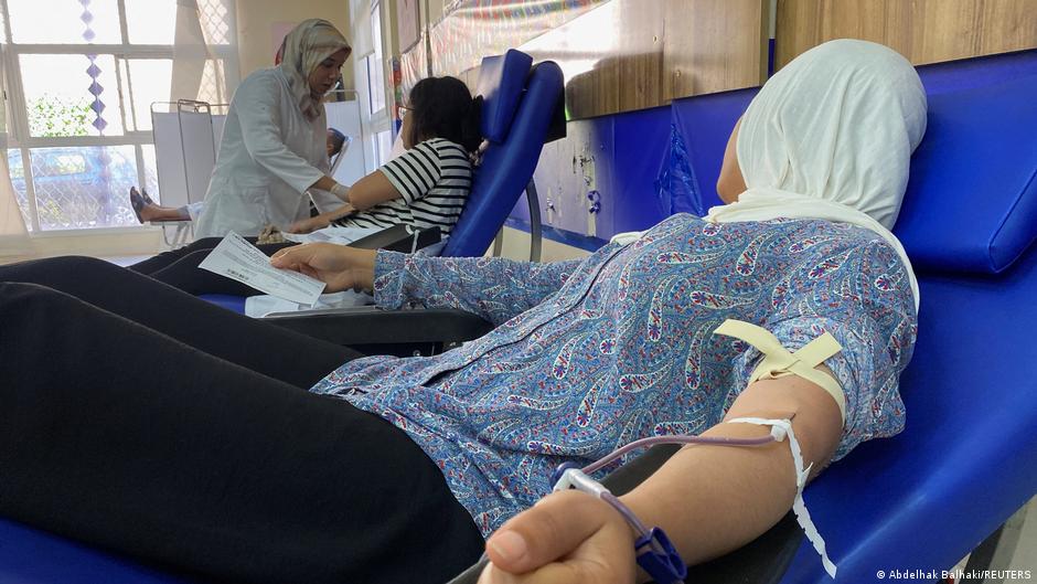 A woman lying on a hospital bed while donating blood