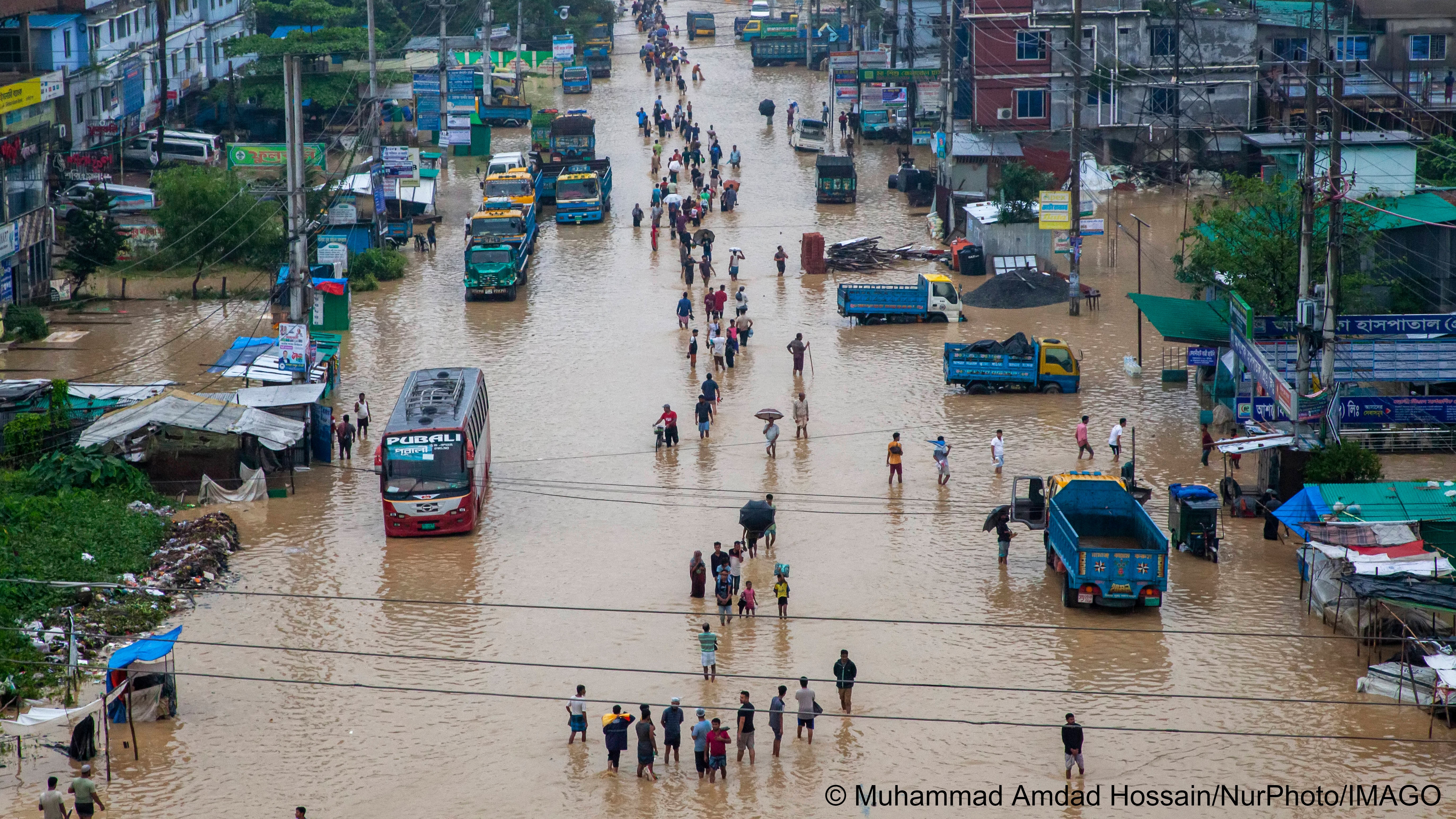 Fußgänger gehen durch überflutete Straßen in Chittagong, Bangladesch, August 2023; Foto: Muhammad Amdad Hossain/NurPhoto/IMAGO