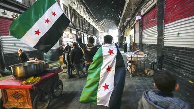 Anhänger der Opposition tragen am Dienstag, dem 10. Dezember 2024, auf dem Al-Hamidiyeh-Markt in der von einer Stadtmauer umgebenen Altstadt von Damaskus, Syrien, Fahnen der Opposition.(Foto: picture alliance / AP| Hussein Malla)