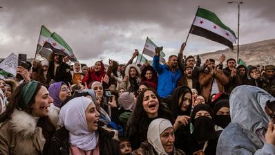 Women and men at a demonstration in Syria with the flag of the revolution