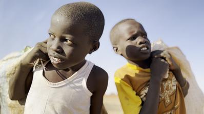 Two young boys carrying bags over their shoulders.