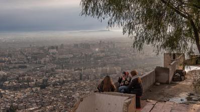 Women sitting on top of Mount Qasioun drinking tea under the shade of a tree.