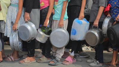 أطفال يحملون الطناجر والصحون ويقفون في طابور 