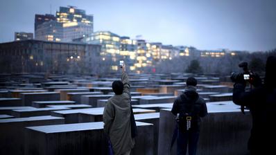 Touristen fotografieren das Holocaustdenkmal in Berlin an einem Winterabend.
