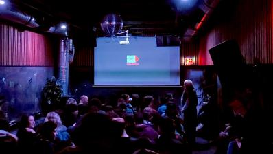 A crowded room full of people. On a screen at the front, the words "Palinale" and a logo.