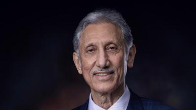 Portrait von Taleb al-Rifai im Anzug vor dunklem Hintergrund.