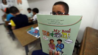 تلميذ يحمل كتاب لتعليم الإنجليزية في فصل مدرسي. (Photo: picture alliance / AP | Fateh Guidoum)