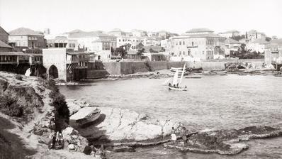 Black and white image of the Beirut seafront, with a sailing boat in the centre.