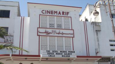 The facade of a building with "Cinema Rif" written in red lettering at the top. Below is a board showing names of films: The Devil Wears Prada 2, Calle Malaga, Super Mario Galaxy.