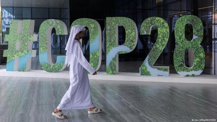 Eine Person in arabischer Kleidung geht an einem "#COP28"-Schild in Abu Dhabi, Vereinigte Arabische Emirate, vorbei
